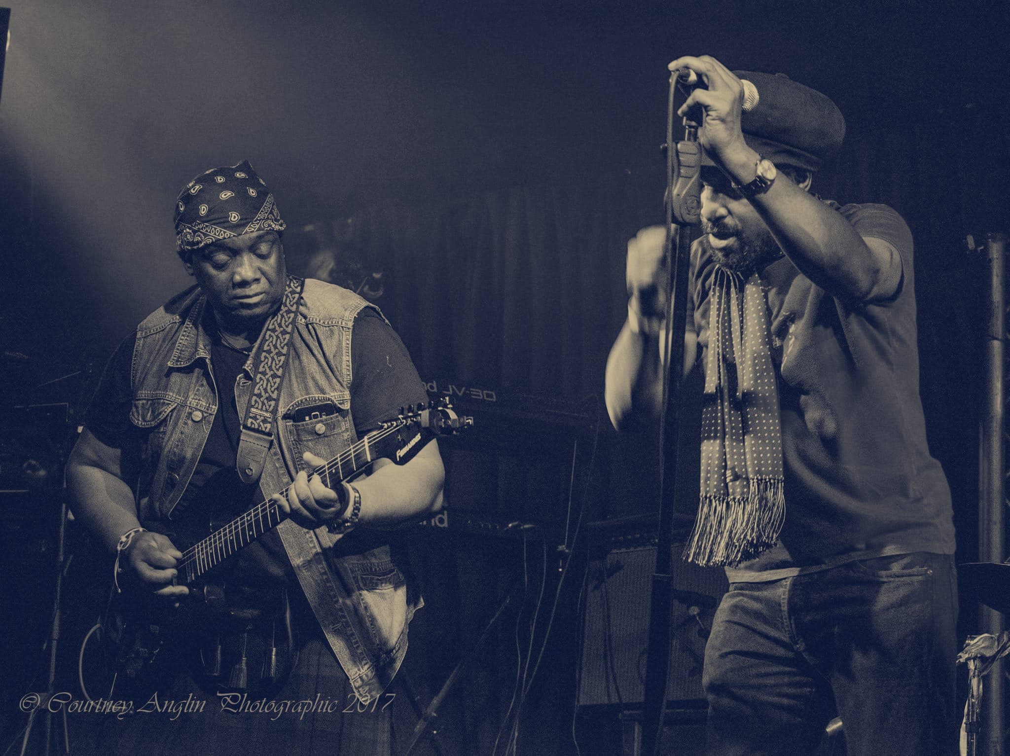 Kareem Shabazz singing beside his guitarist under blue stage light