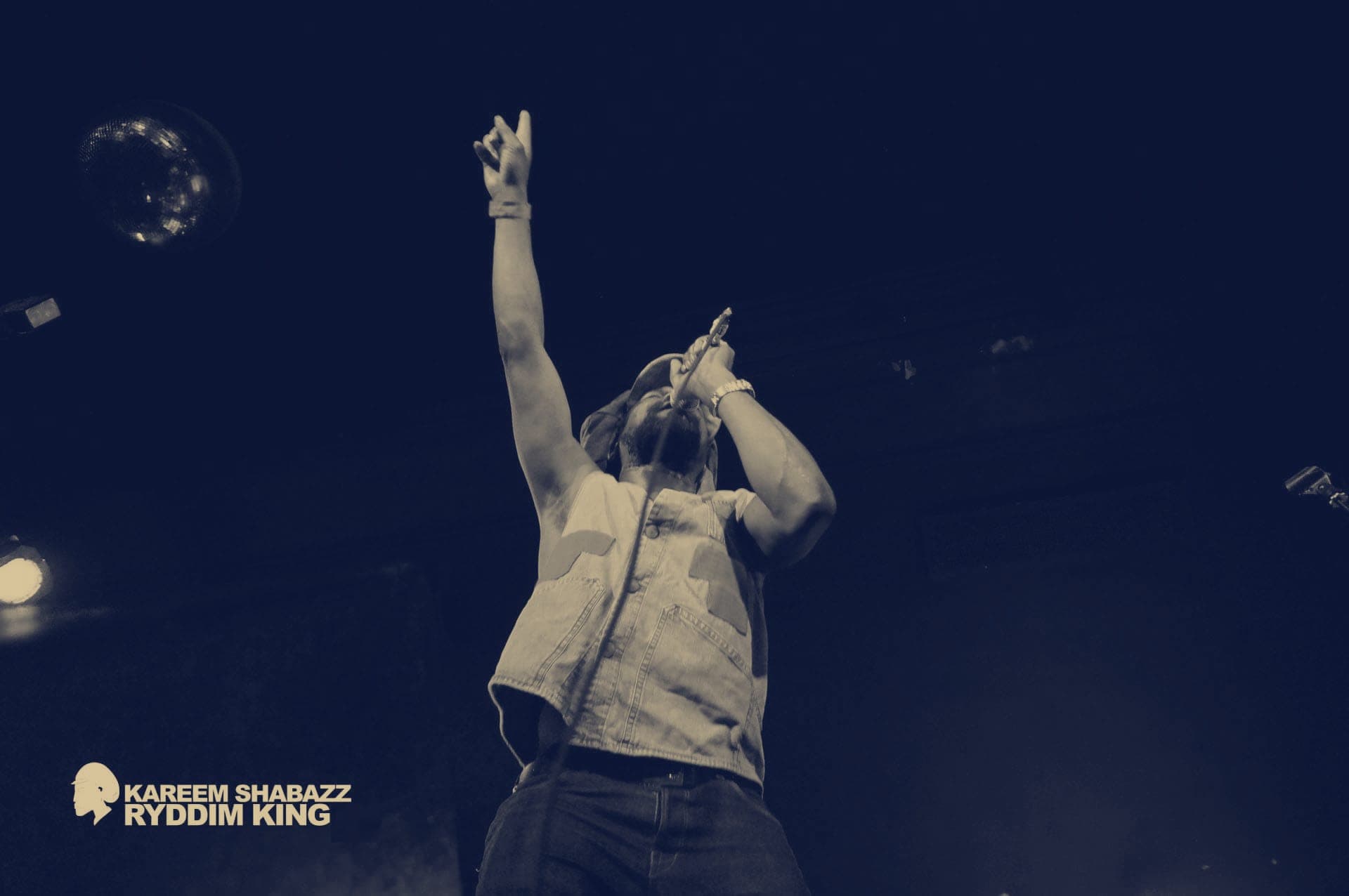 Kareem Shabazz with one arm raised under stage lights